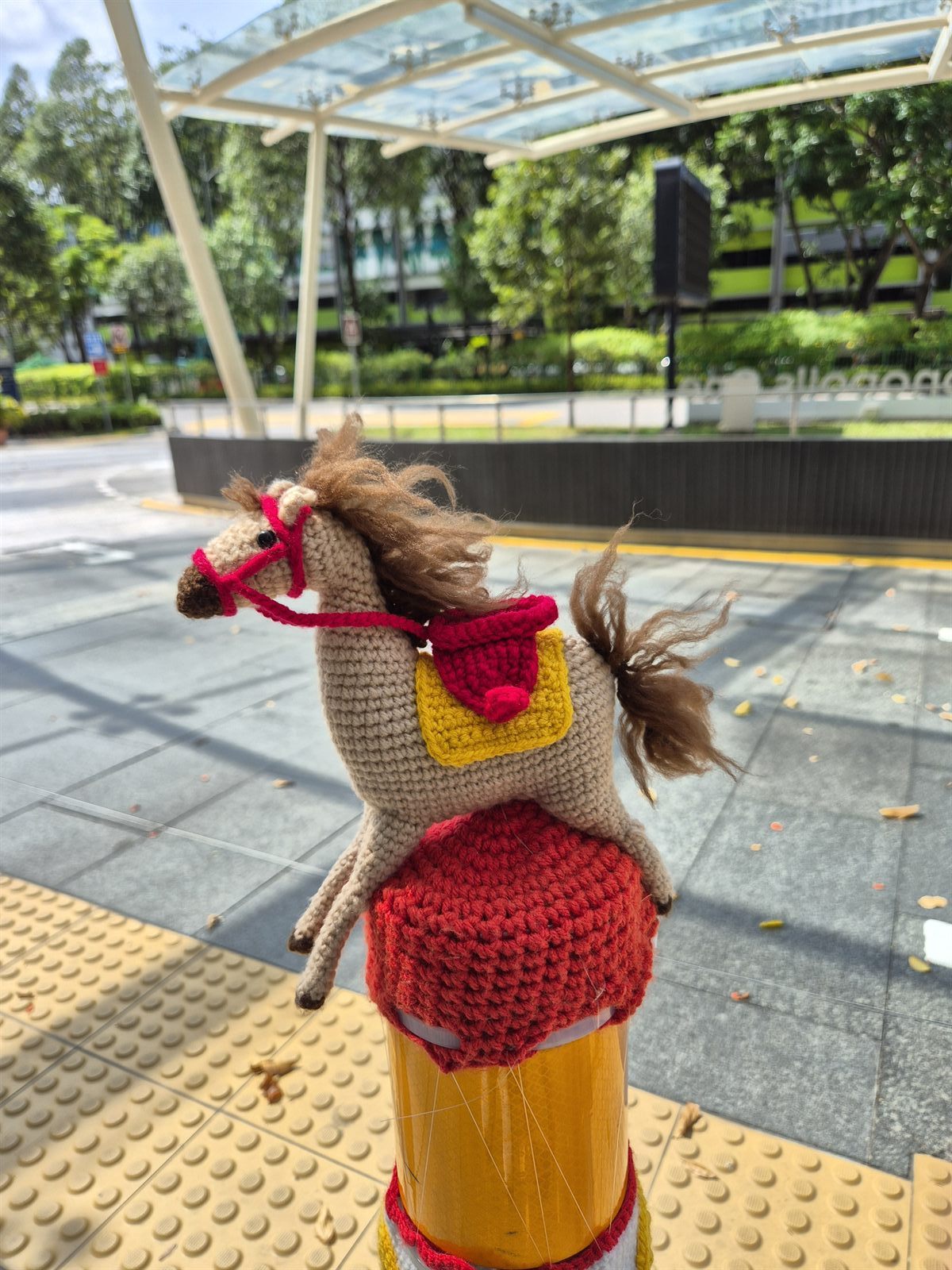 Crocheted horse on a bollard at Fusionopolis One taxi stand, decorated for Chinese New Year 2026.
